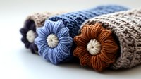 Cozy knitted headband with handmade crochet flowers in blue, brown and beige colors on white background, close up view of winter accessory details.