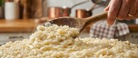 Wooden spoon lifting creamy risotto from a pot in a warm kitchen setting, showcasing Italian cuisine preparation and cooking techniques.