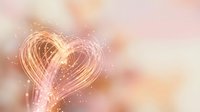 Glowing heart shape made of golden light trails with sparkling particles on soft pink and peach blurred background for romantic designs and love concepts.