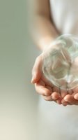 Hands holding transparent glass sphere with swirling green and white liquid inside, symbolizing sustainability, innovation, and environmental care for business concepts.