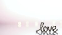 Romantic love script lettering with soft pink bokeh background for wedding invitations and Valentine's Day cards.