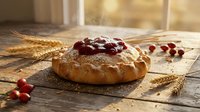 Homemade cranberry bread loaf with fresh berries on rustic wooden table with wheat stalks in warm sunlight for bakery and cooking concepts.