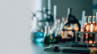 Modern laboratory equipment with glassware and scientific instruments in soft focus creating professional research atmosphere for medical studies.