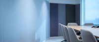 Modern conference room with gray upholstered chairs at wooden table, minimalist interior design, professional meeting space with blue wall lighting and contemporary office furniture.