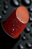 Red makeup sponge with water droplets on dark surface for beauty and cosmetics application.