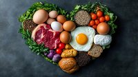 Heart-shaped arrangement of healthy protein foods including eggs, meat, fish, legumes, nuts and vegetables on dark background for balanced nutrition.