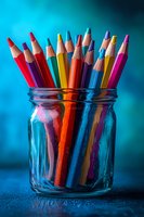 Colorful pencils in glass jar on blue background for creative art projects and educational supplies.