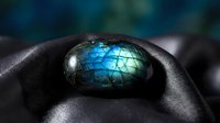 Stunning labradorite gemstone with brilliant blue flash held in protective hands showcasing natural iridescent colors and mystical properties for jewelry design.
