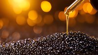 Golden oil drop falling onto black caviar pearls against blurred warm bokeh background, luxury gourmet food close-up macro photography.