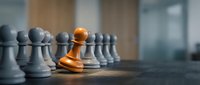 Golden pawn standing out among gray pawns on wooden surface, representing leadership, uniqueness, and competitive advantage in business strategy.