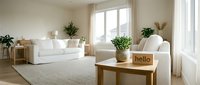 Bright minimalist living room with white sofas, natural light, green plants, and a wooden table with a hello sign in neutral tones.
