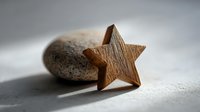 Wooden star decoration on textured surface with smooth stone creating minimalist composition for craft projects and natural home decor styling.