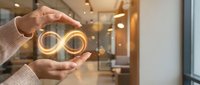 Close-up of hands holding glowing infinity symbol neon light, representing endless possibilities, sustainability, and continuous growth for business and technology concepts.