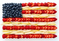 Blueberries and strawberries arranged in flag pattern with banana stripes, patriotic food art for holiday celebrations, nutrition concepts, and festive dining themes.