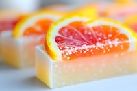 Fresh grapefruit slice garnished with salt crystals atop creamy dessert bar, macro view showing vibrant citrus colors and smooth texture in soft focus.