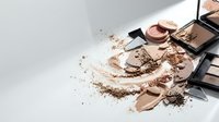 Makeup cosmetics scattered with brown eyeshadow powder and brushes on white background for beauty and fashion design projects.