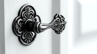 Ornate vintage door handle with floral pattern in black and white, featuring intricate baroque details against light background, selective focus on metalwork design.