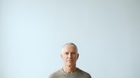 Senior man with white hair and glasses wearing casual beige sweater, isolated on white background for portrait and headshot use.