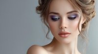 Young Caucasian woman with elegant updo hairstyle and professional purple eyeshadow makeup wearing nude lipstick against soft gray background, beauty and cosmetics concept.