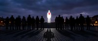 Silhouetted crowd of people facing glowing figure in center at night, symbolizing leadership, inspiration, and standing out from the group for business and motivation concepts.