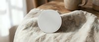 White round cosmetic jar on soft beige textured fabric with natural lighting for skincare product mockup and beauty brand presentation.
