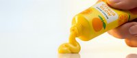 Yellow cooking oil pouring from bottle into puddle on white surface, showing liquid flow and kitchen ingredient use for culinary preparation.