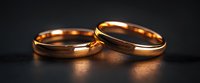 Elegant gold wedding rings on dark background with soft reflection, symbolizing eternal love and commitment. Close up macro photography with selective focus.