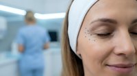Young Caucasian woman with closed eyes and surgical markings around eye area in medical clinic preparing for cosmetic surgery procedure.