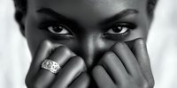 Dramatic black and white portrait of a woman with intense gaze covering lower face with hands, showcasing an ornate ring on her finger.