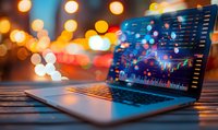 Laptop displaying financial trading charts and stock market data on screen with blurred city lights bokeh background creating atmospheric evening mood.