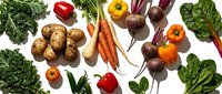Fresh organic vegetables collection with potatoes carrots bell peppers leafy greens and root vegetables on white background for healthy cooking recipes.