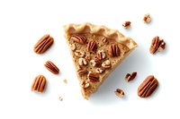 Slice of homemade pecan pie with whole nuts scattered around on white background, top view. Traditional southern dessert photographed from above, isolated.