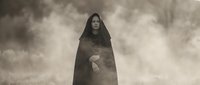 Mysterious hooded figure in dark cloak standing in foggy atmospheric environment. Gothic fantasy character for horror themed projects and supernatural storytelling.