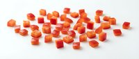 Fresh diced carrots cut into small cubes scattered on white background, perfect for cooking recipes and healthy meal preparation ingredients.