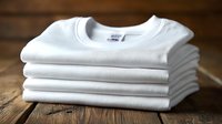 Stack of folded white cotton t-shirts on wooden surface, ready for casual wear, branding, or customization.