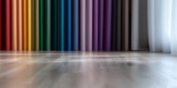 Blurred wooden floor with colorful vertical stripes on wall creating rainbow gradient effect in empty room, soft focus background with selective depth of field.