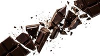 Dark chocolate pieces shattering and exploding in mid-air with fragments flying against white background, suitable for food and beverage advertising.
