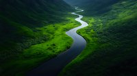 Meandering river flows through lush green valley with dramatic mountain slopes creating natural S-curve pattern in remote wilderness landscape.