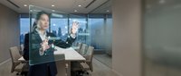 Diverse business professionals collaborate on digital interface in modern office with city skyline view, representing teamwork and technology integration.