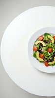 Fresh mixed green salad with avocado slices and cherry tomatoes served on white plate, healthy vegetarian meal for restaurant menu design.