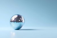 Shiny disco ball reflecting light on soft blue background with copy space, minimalist party and celebration concept for entertainment designs.
