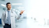 Professional male doctor with stethoscope pointing gesture in modern hospital corridor for medical presentations and healthcare marketing materials.