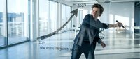 Confident businessman in suit celebrating success with arms outstretched in modern office with city view. Corporate achievement and goal accomplishment concept.