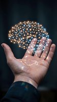 Glowing brain with illuminated neural network connections held in open palm against dark background, representing artificial intelligence, innovation, and digital technology concepts.