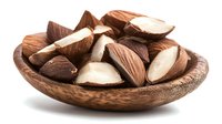Mixed Brazil nuts in wooden bowl isolated on white background for healthy snacking and cooking recipes.