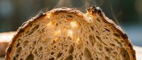 Freshly baked artisan bread loaf with golden crust and airy crumb structure, ideal for bakery, food, and culinary design projects.