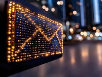 Glowing LED display showing email envelope symbol against blurred city lights background, representing digital communication and connectivity in modern urban setting.