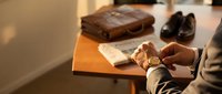 Professional businessman checking time on luxury watch while preparing for important business meeting with leather briefcase and formal shoes.