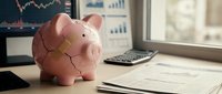 Pink piggy bank on office desk with financial charts and calculator representing savings and budget planning for business investment goals.