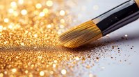 Makeup brush with scattered gold glitter powder on light surface against shimmering bokeh background, creating luxurious cosmetic artistry effect.